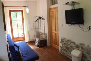a living room with a blue couch and a tv on a wall at Penzion Gomelská in Horní Stropnice