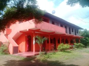 czerwony budynek z palmą przed nim w obiekcie Sayonara Resort w mieście Hambantota