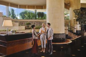 a group of three people standing in a lobby at JW Marriott Hotel Surabaya in Surabaya