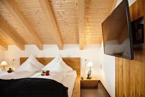 a bedroom with a bed with white pillows and a flat screen tv at Hirschbergblick - fewo-badhindelang in Bad Hindelang