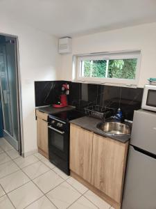 a small kitchen with a sink and a microwave at Studio avec jardin clos in Verton +5 photos