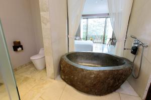 La salle de bains est pourvue d'une grande baignoire en bois et de toilettes. dans l'établissement Tejaprana Resort & Spa, à Ubud