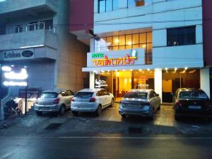 a parking lot with cars parked in front of a building at Hotel Vaikunth By Adamo in Nāthdwāra