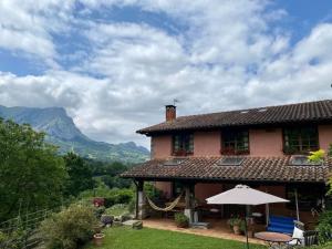 a house with an umbrella and mountains in the background at Utsusabar baserria in Inza