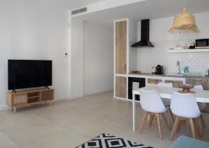 ein Wohnzimmer mit Fernseher und Tisch und Stühlen in der Unterkunft Apartamento Maria Benlliure in Bellreguart