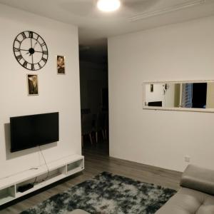 sala de estar con TV y reloj en la pared en AZK HOMESTAY, en Sungai Besar