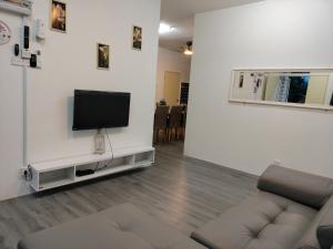 a living room with a couch and a tv on a wall at AZK HOMESTAY in Sungai Besar