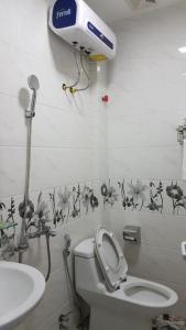 a bathroom with a toilet and a blow dryer on the wall at Love Hotel Hà Đông HN - by BAY LUXURY in Hà Ðông