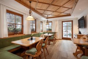 a restaurant with wooden tables and chairs and windows at Obersulzberggut in Radstadt