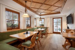 ein Restaurant mit Holztischen, Stühlen und Fenstern in der Unterkunft Obersulzberggut in Radstadt
