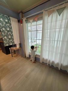 ein kleines Kind steht vor einem Fenster in der Unterkunft Hello minbak in Boseong