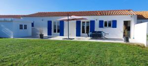 a white and blue house with an umbrella at Maison neuve 6/8p à La Cotinière in La Cotinière