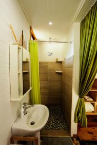 a bathroom with a sink and a green shower curtain at Pequena Casa Holiday Home Malongane in Ponta Malongane