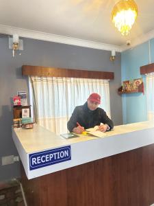 Ein Mann sitzt an der Rezeption. in der Unterkunft Hotel The Billabong Garden Pokhara in Pokhara