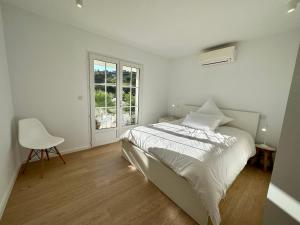 a white bedroom with a bed and a chair at Villa Les Palmiers St. Maxime in Sainte-Maxime