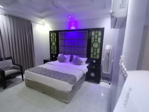 a bedroom with a large bed with a purple light at Golden New Al Dar - جولدن نيو الدار in Jazan