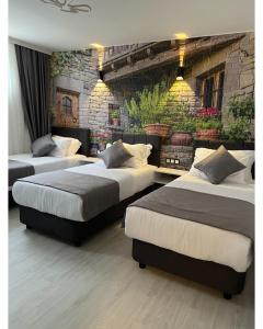 drie bedden in een kamer met een bakstenen muur bij My Dream Bozcaada in Bozcaada