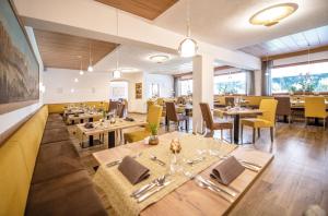 ein Restaurant mit Holztischen und gelben Stühlen in der Unterkunft APIPURA hotel rinner in Oberbozen