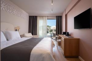 a hotel room with a bed and a flat screen tv at Oniro Boutique Hotel in Toroni