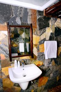 Baño de piedra con lavabo y espejo en Coco Village Hotel Chilaw, en Chilaw