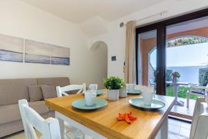 uma sala de jantar e sala de estar com uma mesa de madeira e cadeiras em Appartamento Borgo Mari PT5 - MyHo Casa em Santa Teresa Gallura