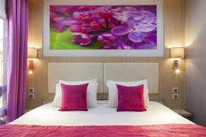 Un dormitorio con una cama con almohadas rosas y una pintura en FH Confort Hotel Orléans Co'met, en Orléans