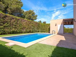 a swimming pool in a yard next to a hedge at Casa Marco Polo in Cala Mendia