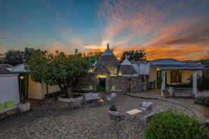 a house with a patio with a sunset in the background at Trulli Li Cridd in Ceglie Messapica