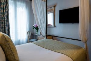 Una habitación de hotel con una cama y un televisor de pantalla plana. en Villa Alessandra, en París