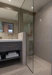 a bathroom with a shower and a sink and a mirror at Oniro Boutique Hotel in Toroni