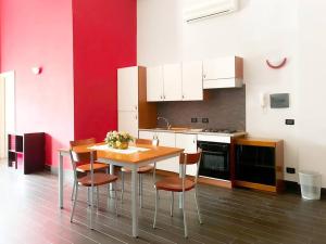 cocina con mesa, sillas y paredes rojas en Mini Appartamento Cutura Rende, en Rende