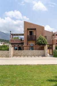 a brown house with a stone wall and a sidewalk at Plakias Resorts in Plakias