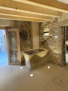 Habitación con pared de piedra y bañera de piedra. en Cal Vallverdú - Adaptado, en Preixana