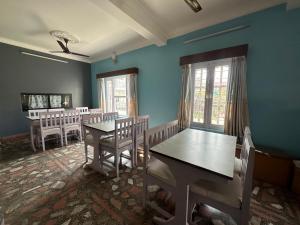 une salle à manger avec des murs bleus, des tables et des chaises dans l'établissement Hotel The Billabong Garden Pokhara, à Pokhara
