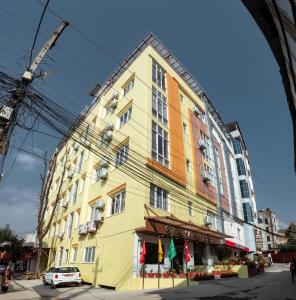 żółty budynek na ulicy z samochodem z przodu w obiekcie Kusum Airport Hotel w Katmandu