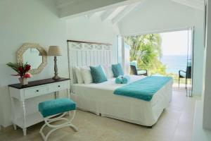 a white bedroom with a bed and a mirror at Lovely 3 BR Ocean View Villa in Cap Estate