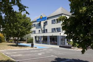 a hotel with a parking lot in front of it at Comfort Hotel Orléans Olivet in Olivet