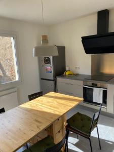 a kitchen with a wooden table and two chairs at Aux Volets Bleus Romanech-thorins in Romanèche-Thorins