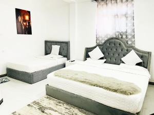 Chamsha Hotel في أنورادابورا: سريرين في غرفة بجدران بيضاء