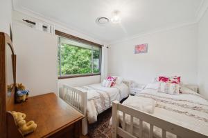 1 dormitorio con 2 camas, mesa y ventana en Azalea Cottage, Leura NSW Australia en Leura
