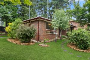 ceglany dom z dwoma drzewami na podwórku w obiekcie Azalea Cottage, Leura NSW Australia w mieście Leura
