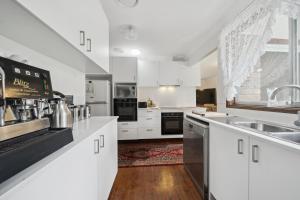 una cocina con armarios blancos y electrodomésticos negros en Azalea Cottage, Leura NSW Australia, en Leura
