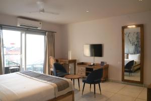 a hotel room with a bed and a desk and a mirror at Ariena by Spree Hotels Goa in Morjim