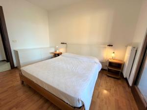 a bedroom with a white bed and two night stands at Isola della Schiusa in Grado