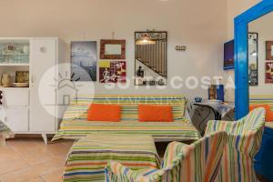 Schlafzimmer mit einem Bett mit orangefarbenen Kissen und Stühlen in der Unterkunft Casa Mimy (Piano Terra) - 700 mt dal mare in Porto Cesareo