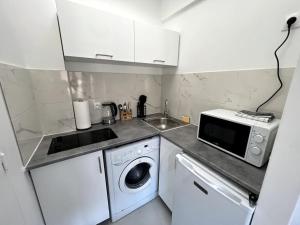 a kitchen with a washing machine and a microwave at Studio cozy proche Paris in Gentilly