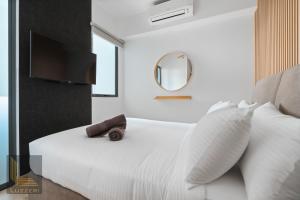 een slaapkamer met een wit bed en een spiegel bij Colony Chow Kit Guesthouse in Kuala Lumpur