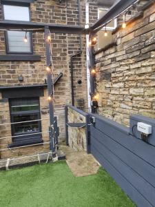 a patio with a brick wall with lights and grass at The Comfy House in Huddersfield