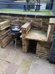 a stone wall with a grill and a bench at The Comfy House in Huddersfield