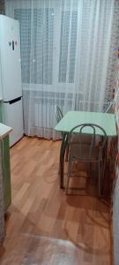 La cuisine est équipée d'une table, d'une chaise et d'un réfrigérateur. dans l'établissement Темиртау 7 микрорайон 1а, à Temirtaū